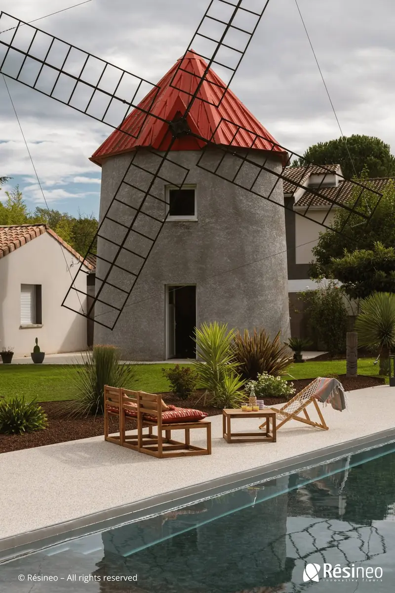 Moquette de pierre autour d'une piscine — moulin en arrière-plan